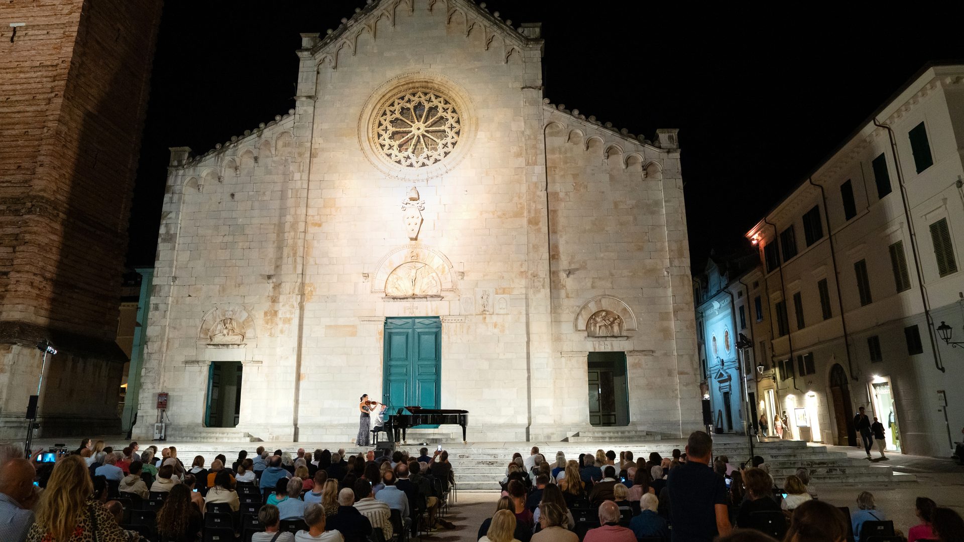 The cathedral in Pietrasanta at night, with the concert on its steps and the audience in the square